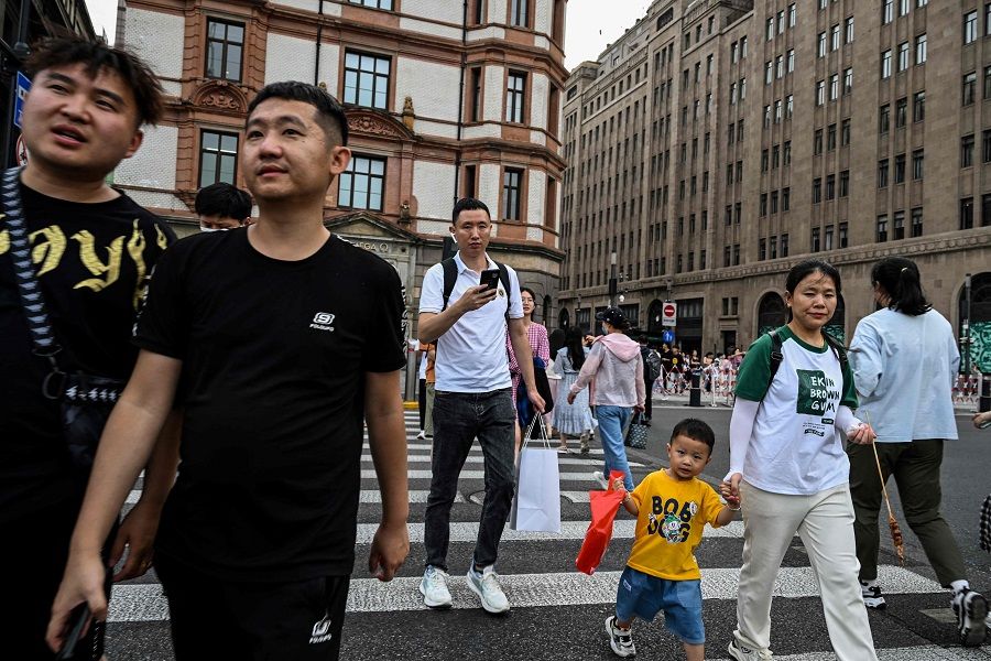 People cross a street on the Bund in the Huangpu district in Shanghai, China, on 15 June 2023. (Hector Retamal/AFP)