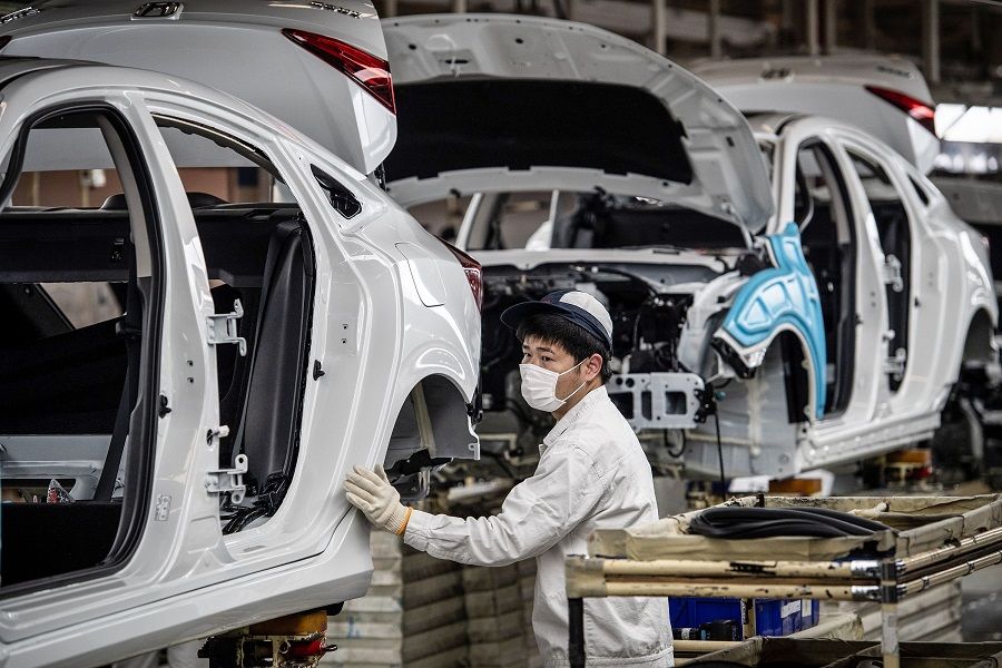 This photo taken on 23 March 2020 shows an employee wearing a face mask working on an assembly line at an auto plant of Dongfeng Honda in Wuhan in China's central Hubei province, as the country slowly gets back to work. (STR/AFP)