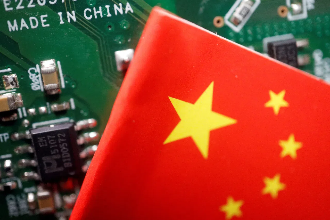 A Chinese flag is displayed next to a “Made in China” sign seen on a printed circuit board with semiconductor chips, in this illustration picture taken 17 February 2023. (Florence Lo/Reuters)