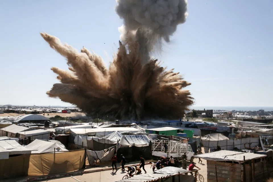People run for cover as a plume of smoke rises above tents at a camp for displaced Palestinians in northern Khan Yunis in the southern Gaza Strip, during an Israeli strike on 19 April 2025. (AFP)