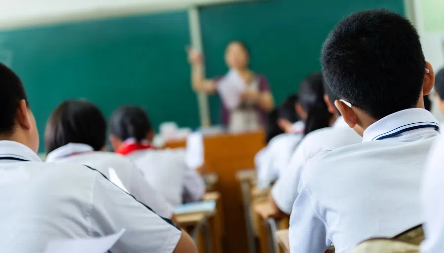 Rear view of students studying in a classroom.