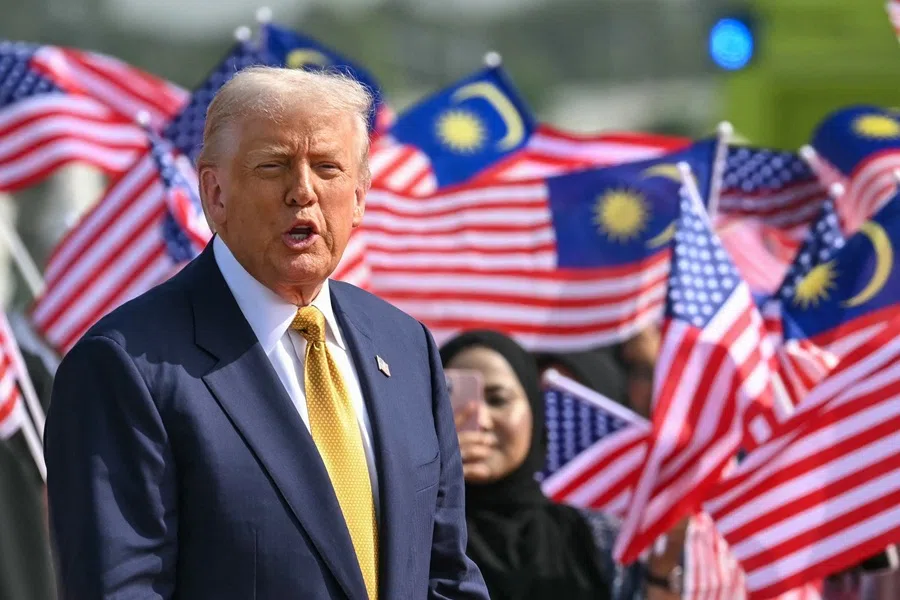 US President Donald Trump looks on next to people waving Malaysian national flags before he departs on Air Force One from Kuala Lumpur International Airport in Sepang on 27 October 2025.