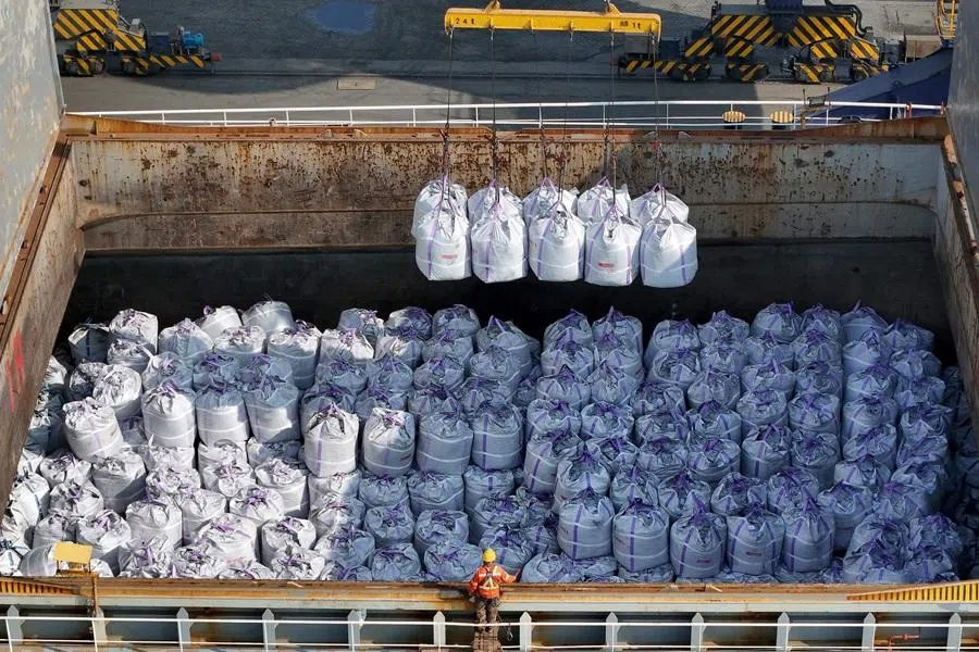 A worker directs the loading of bagged bulk urea fertiliser for export at a port in Yantai, in China's eastern Shandong province, on 13 April 2026. (AFP)