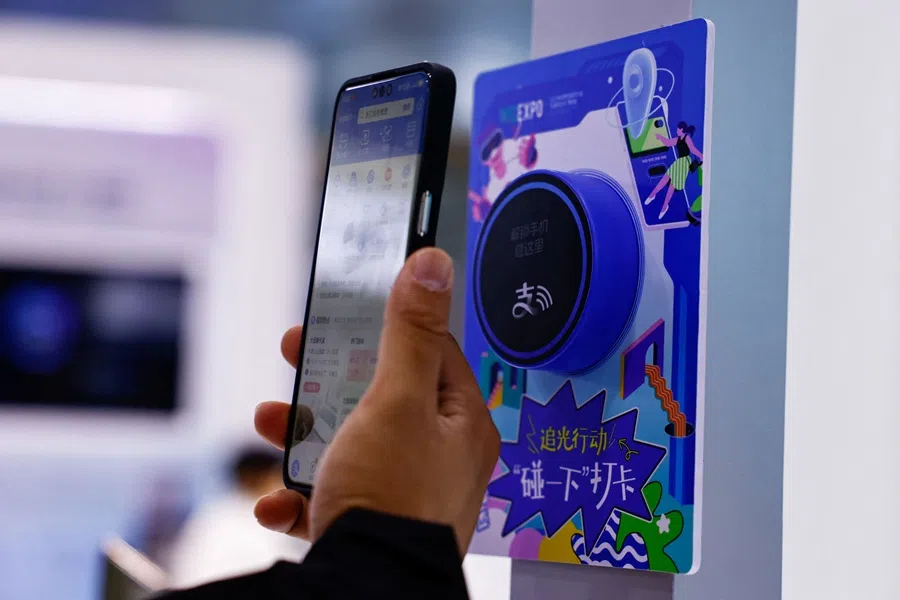 A visitor taps his phone near an Alipay contactless terminal to check in at the Alibaba booth, at the expo of the World Internet Conference in Wuzhen, Zhejiang province, China, on 8 November 2025. (Tingshu Wang/Reuters)
