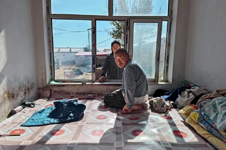 Li Bulin, who has some disability in his legs, sits on his bed. He makes his living by growing an oil crop. (Fan Qiaojia/Caixin)
