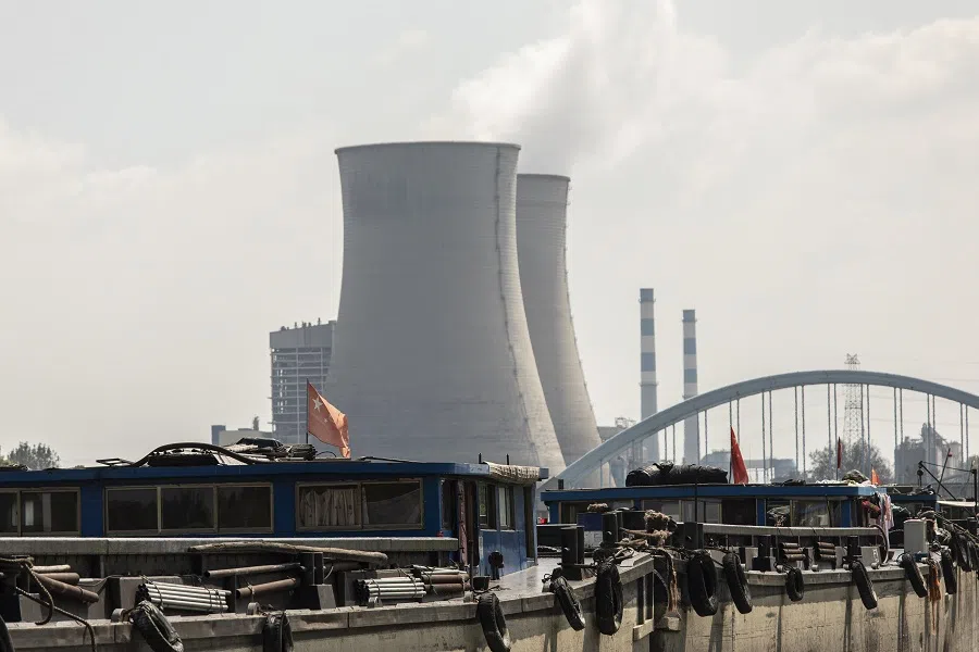 A barge with Chinese flags travels past the Wangting Power Plant in Wangting, Jiangsu province, China, on 30 September 2021. (Qilai Shen/Bloomberg)