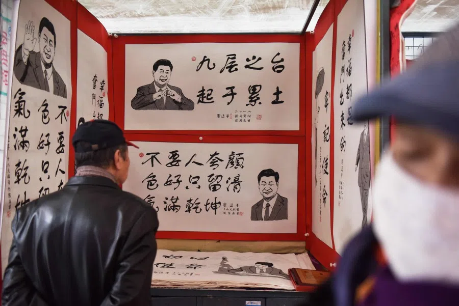 In this file photo taken on 26 February 2018, people look at posters featuring drawings of China's President Xi Jinping and his quotes at a market in Beijing. (Greg Baker/AFP)