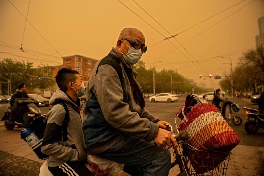 A man and a boy ride on an electric bike during a sandstorm in Beijing on 15 April 2021. (Nicolas Asfouri/AFP)