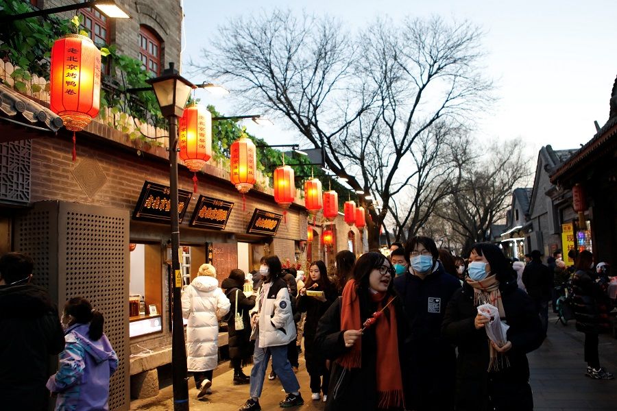 People walk past shops in a hutong alley in Beijing, China, 31 December 2022. (Florence Lo/Reuters)