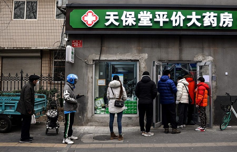 People queue to buy medicine at a drug store in Beijing, China, on 9 December 2022. (Noel Celis/AFP)