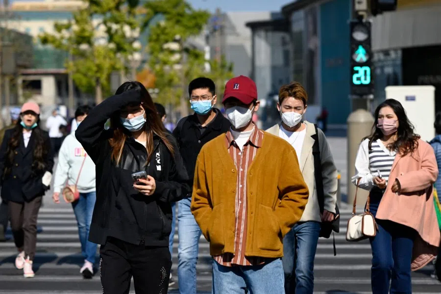 Pedestrians cross a street in the financial district in Beijing on 24 October 2022. (Wang Zhao/AFP)