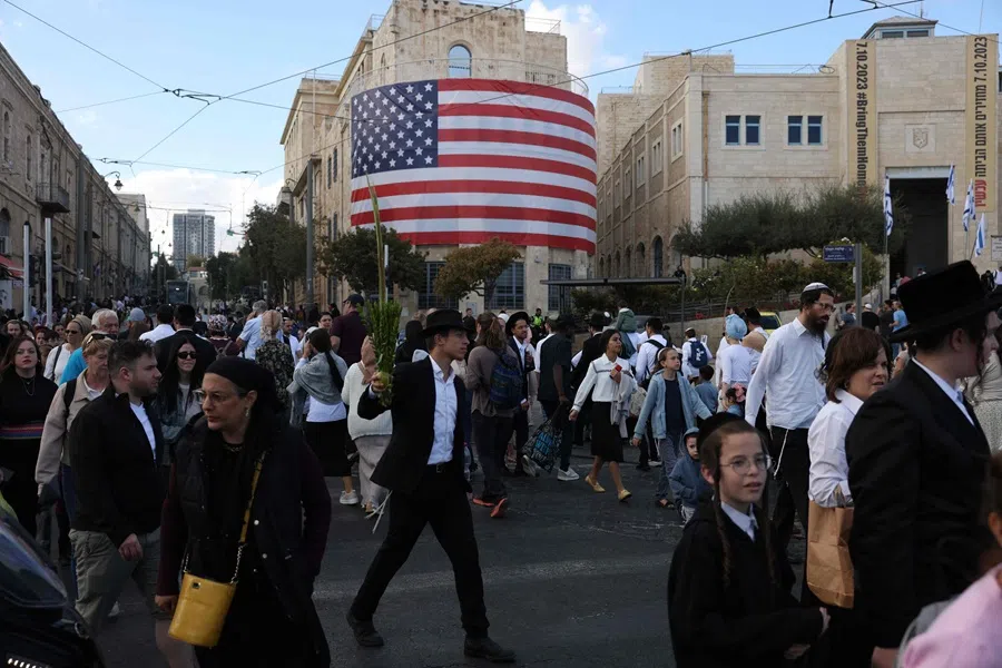 Israelis walk past a US flag in the heart of Jerusalem on 12 October 2025.