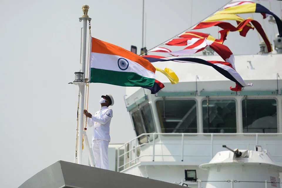 A coast guard official raises the Indian national flag on board the Indian Coast Guard offshore patrol vessel "Vajra" during its commissioning ceremony, in Chennai, India, on 24 March 2021. (Arun Sankar/AFP)