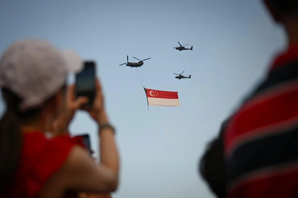 People watch the iconic state flag flypast during Singapore’s National Day Parade on 9 August 2025. (SPH Media)
