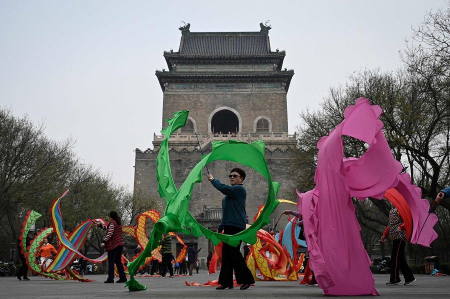 People wave ribbons in front of a historic building in Beijing, China, on 17 November 2021. (Jade Gao/AFP)