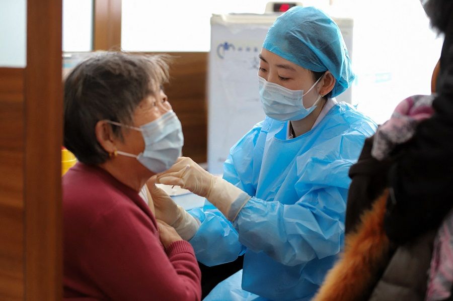 This photo taken on 9 January 2022 shows a resident (left) receiving a booster shot of the Sinovac Covid-19 vaccine in Rongcheng, Shandong province, China. (AFP)
