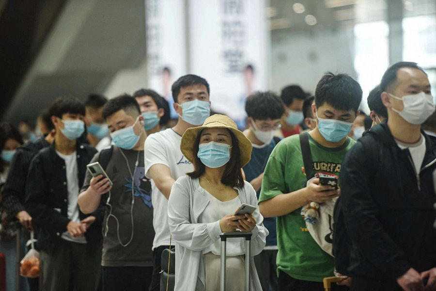 Passengers use their mobile phones as they prepare to board trains at Hangzhou East train station in Hangzhou, Zhejiang province, China on 30 April 2021. (STR/AFP)