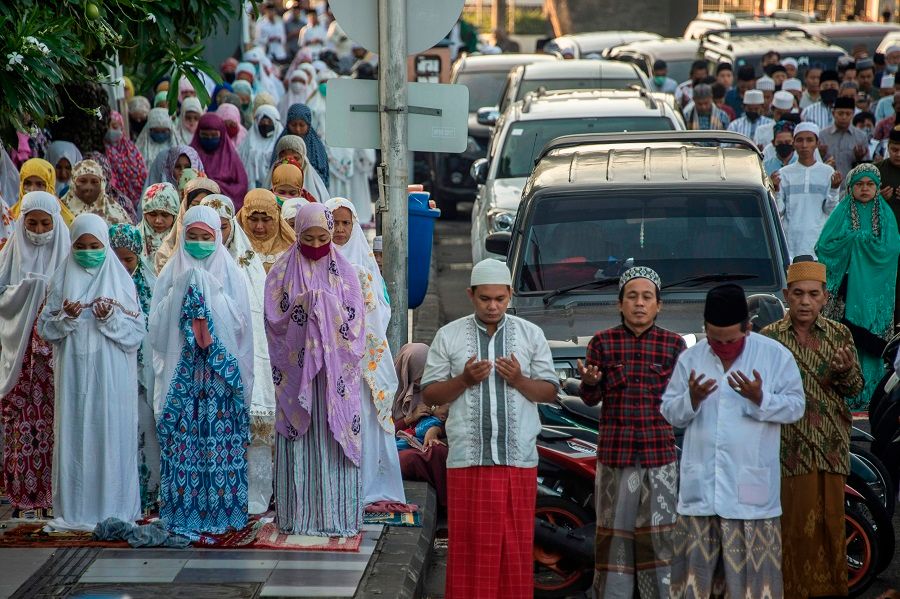 Indonesians attend Eid al-Fitr prayers, marking the end of the Muslim holy month of Ramadan, on a street in Surabaya on 24 May 2020. (Juni Kriswanto/AFP)