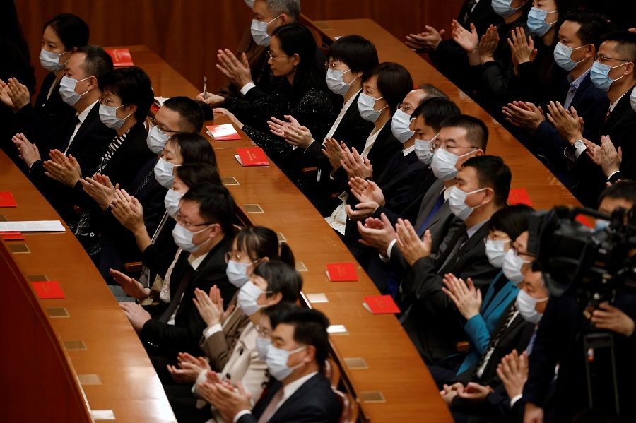 Chinese delegates wearing face masks applaud at a meeting commemorating the 110th anniversary of Xinhai Revolution at the Great Hall of the People in Beijing, China, 9 October 2021. (Carlos Garcia Rawlins/Reuters)