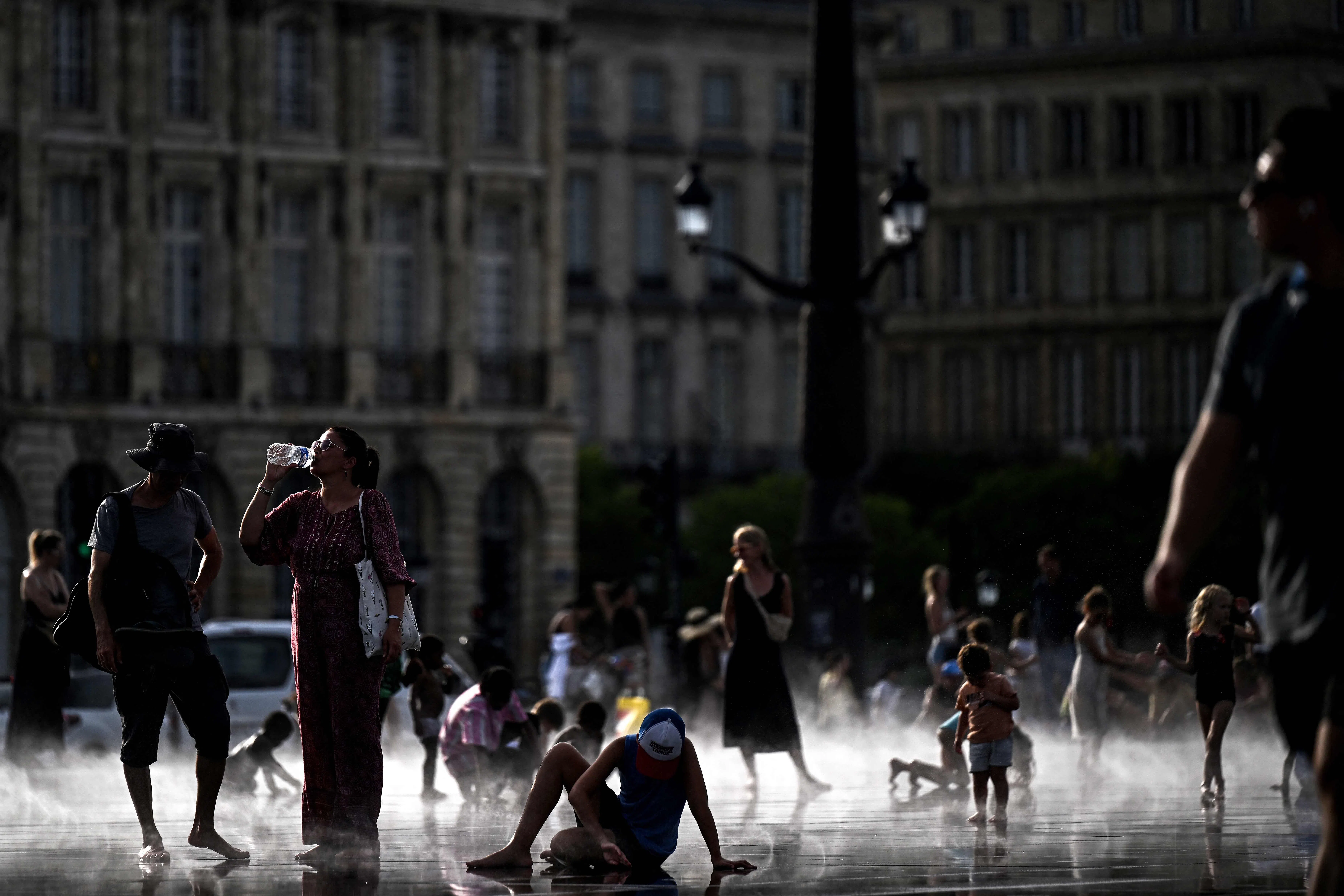 A pedestrian drinks water on the Miroir d'eau reflecting pool amid a heatwave, in Bordeaux, southwestern France, 12 July 2026.
