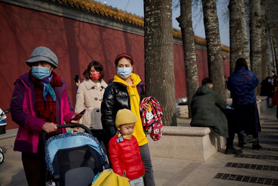 People wearing face masks wait near Tiananmen Gate in Beijing, China, on 12 February 2021. (Noel Celis/AFP)
