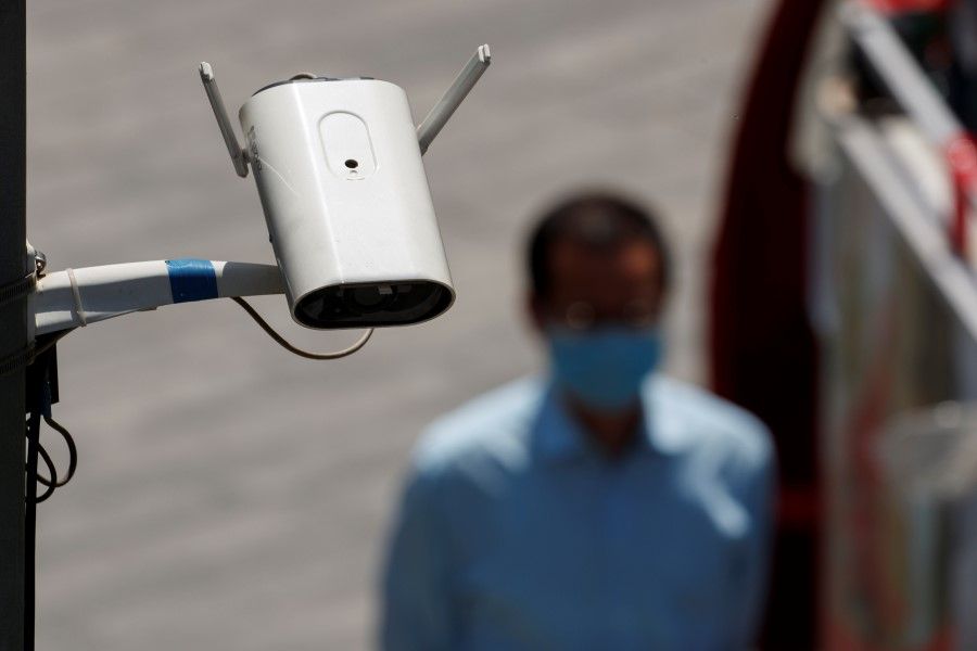 A CCTV security surveillance camera overlooks a street as a man walks past following the spread of the coronavirus disease (COVID-19) in Beijing, 11 May 2020. (Thomas Peter/REUTERS)