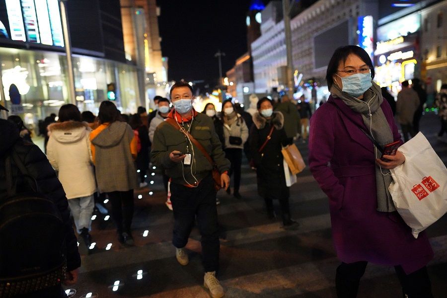 People walk along a shopping street in Beijing, China, 24 December 2020. (Tingshu Wang/Reuters)