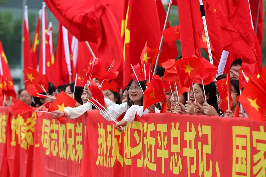 People wave Chinese and Vietnamese national flags ahead of the arrival of Chinese President Xi Jinping and his wife Peng Liyuan at Noi Bai International Airport in Hanoi, Vietnam on 12 December 2023. (Luong Thai Linh/Pool/AFP)