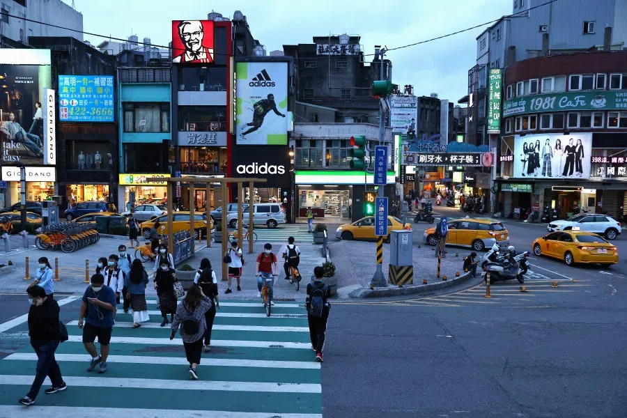 People wear protective face masks while crossing the street amid the Covid-19 pandemic, in Taoyuan, Taiwan, 12 May 2021. (Ann Wang/Reuters)