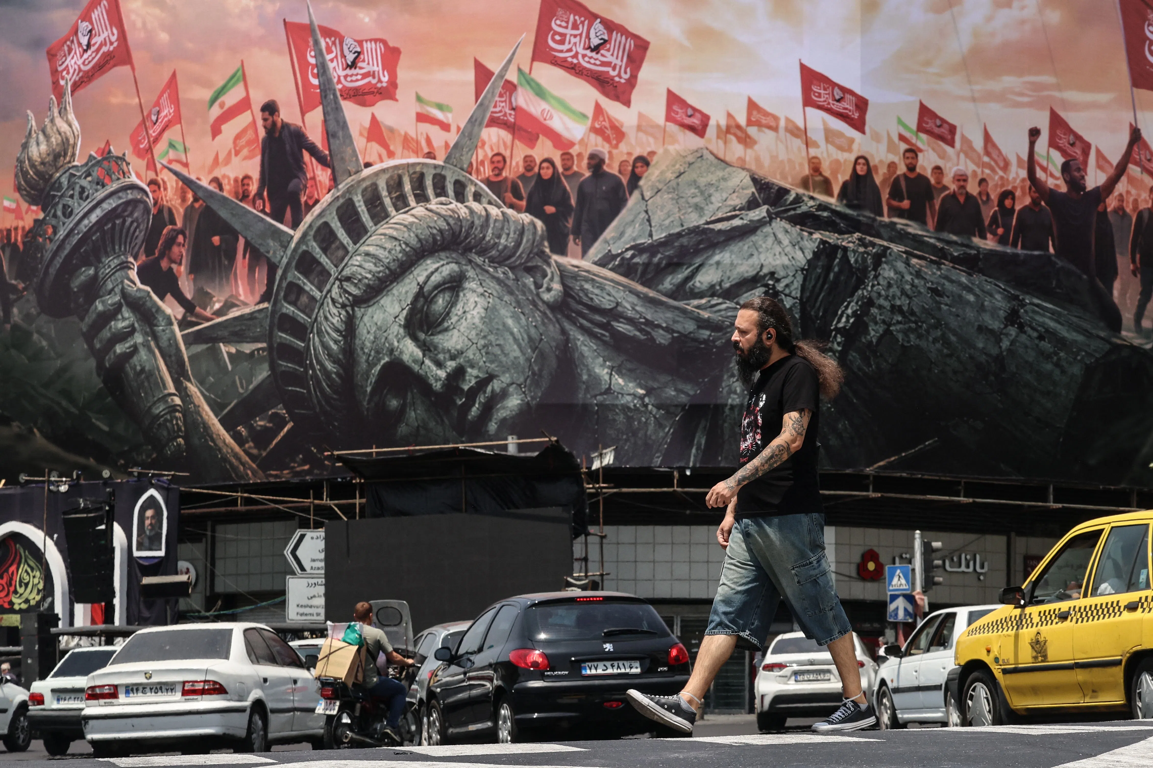 An Iranian man walks past an anti-US billboard at Enghelab Square in central Tehran on 3 August 2026.