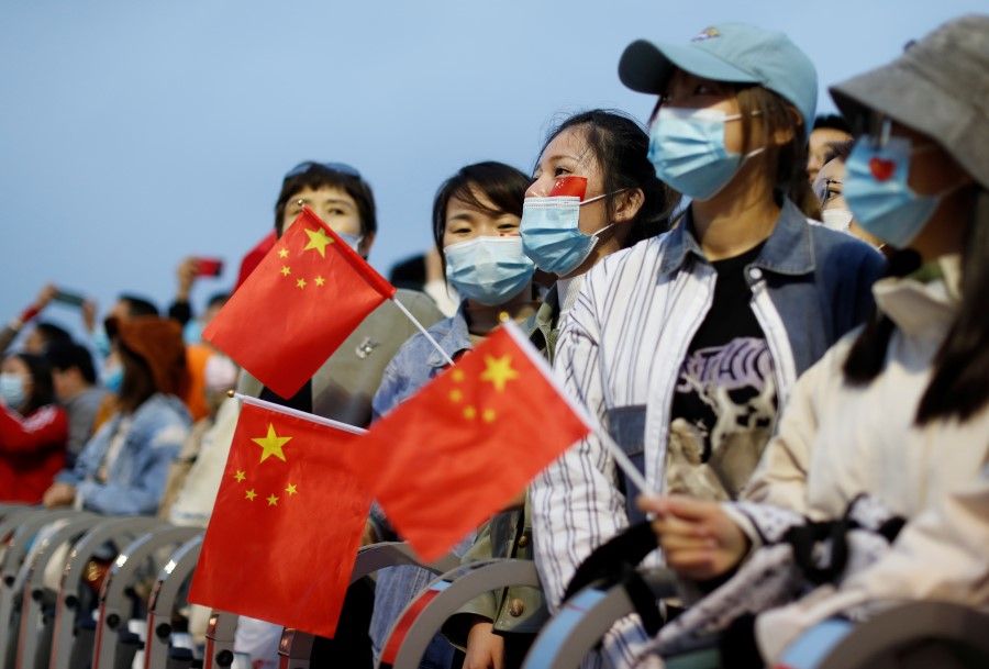 People wearing face masks, following the coronavirus disease (Covid-19) outbreak, hold China flags attend a flag-raising ceremony at Tiananmen Square on National Day to mark the 71st anniversary of the founding of People's Republic of China, in Beijing, China, 1 October 1, 2020. (Carlos Garcia Rawlins/REUTERS)
