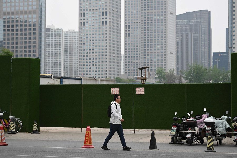 A man walks past the entrance to a construction site in Beijing, China, on 23 March 2023. (Greg Baker/AFP)