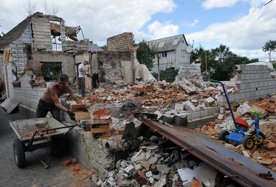 A man moves bricks during the reconstruction of a destroyed home in the small town of Makariv, Kyiv region, Ukraine on 15 June 2022. (Sergei Chuzavkov/AFP)