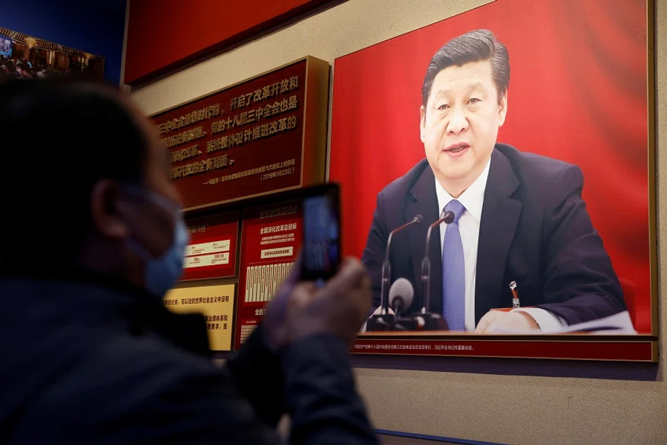 A man holds a mobile phone in front of an image of Chinese President Xi Jinping displayed at the Museum of the Communist Party of China in Beijing, China, 11 November 2021. (Carlos Garcia Rawlins/Reuters)