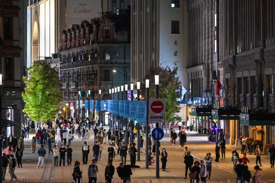 People walk along a pedestrian street surrounded by shops and shopping malls in Shanghai on 24 October 2022. (Hector Retamal/AFP)