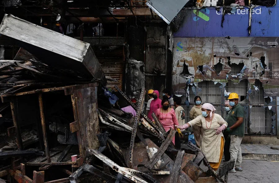 Staff members from Bhat-Bhateni Supermarket work to clear debris from the ransacked building that was torched, following the protest against anti-corruption triggered by a social media ban in Kathmandu, Nepal, on 14 September 2025. (Navesh Chitrakar/Reuters)