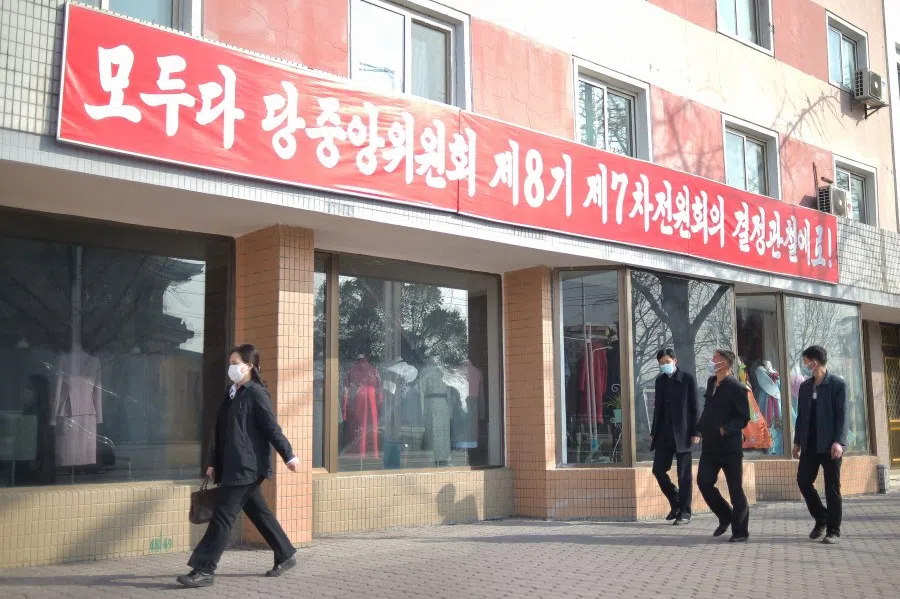 People walk past a banner with a slogan that translates as "Let us strive for the implementation of the decisions of the 7th Plenary meeting of 8th WPK Central Committee" in Pyongyang on 31 March 2023. (Kim Won Jin/AFP)