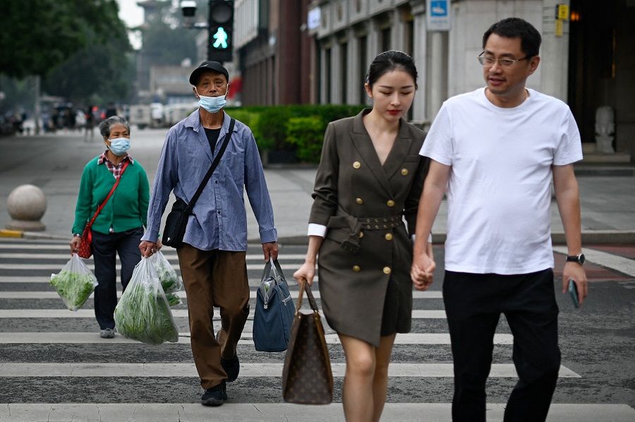 People walk across a street in Beijing, China, on 31 May 2021. (Wang Zhao/AFP)