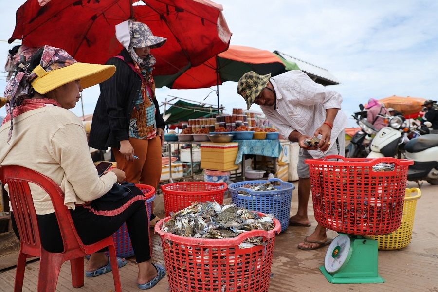 A fisherman weighs crabs at a seafood market in Kep province, Cambodia, on 17 August 2023. (Thomas Suen/Reuters)