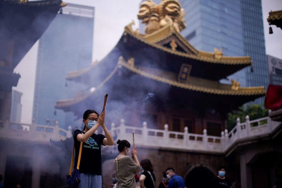 People wearing face masks worship at the Buddhist Jing'an Temple in Shanghai, China, 18 July 2020. (Aly Song/Reuters)