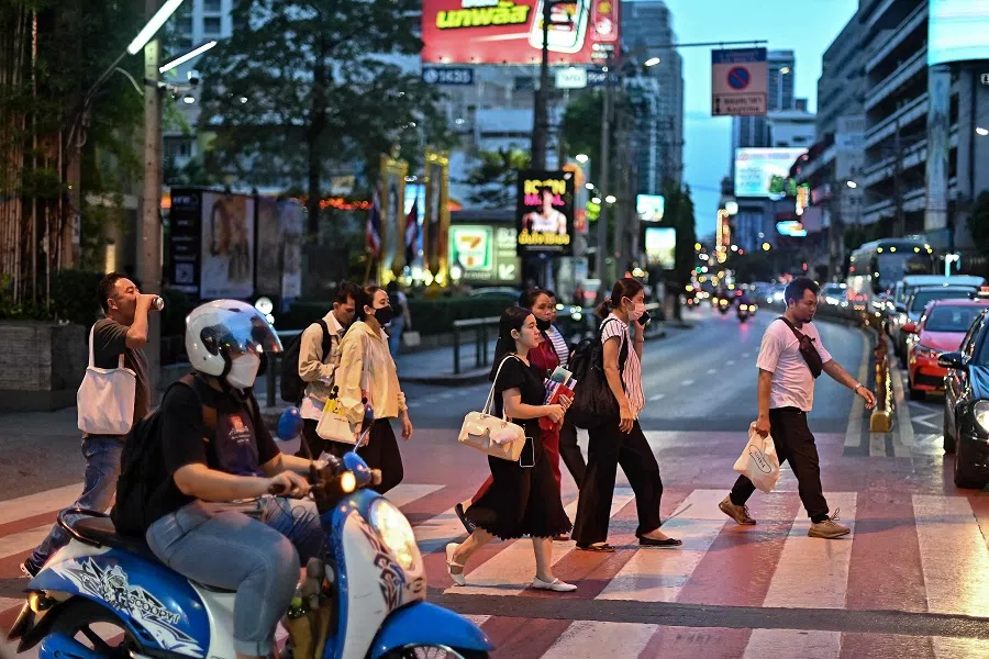 Pedestrians cross a busy street in Bangkok on 21 August 2024. (Manan Vatsyayana/AFP)