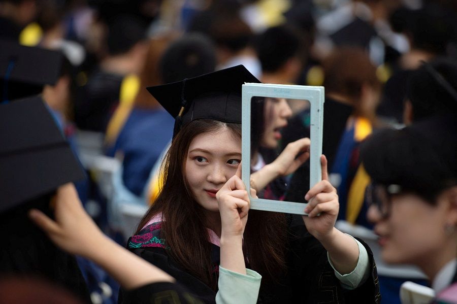 A girl poses for a photograph at a graduation ceremony at Central China Normal University in Wuhan, Hubei province, China, 13 June 2021. (Stringer/Reuters)