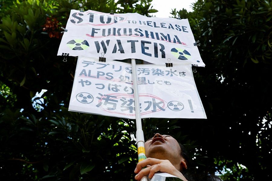 A protester holds signs during a rally against the discharging of treated radioactive water from the crippled Fukushima Daiichi nuclear plant into the ocean, in front of Prime Minister Fumio Kishida's official residence in Tokyo, Japan, on 25 August 2023. (Kim Kyung-Hoon/Reuters)