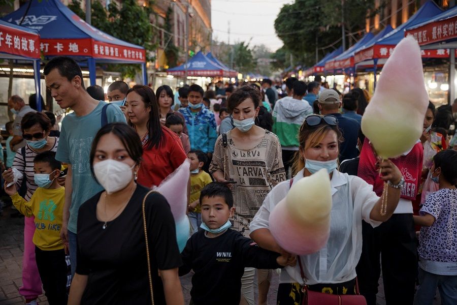 People walk in a night market during the Labour Day holidays tourist rush in the old city in Kashgar, Xinjiang Uyghur Autonomous Region, China, 2 May 2021. (Thomas Peter/Reuters)