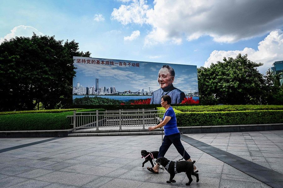 This photo taken on 13 July 2022 shows a woman walking past a poster of late Chinese leader Deng Xiaoping in Shenzhen, Guangdong province, China. (Jade Gao/AFP)