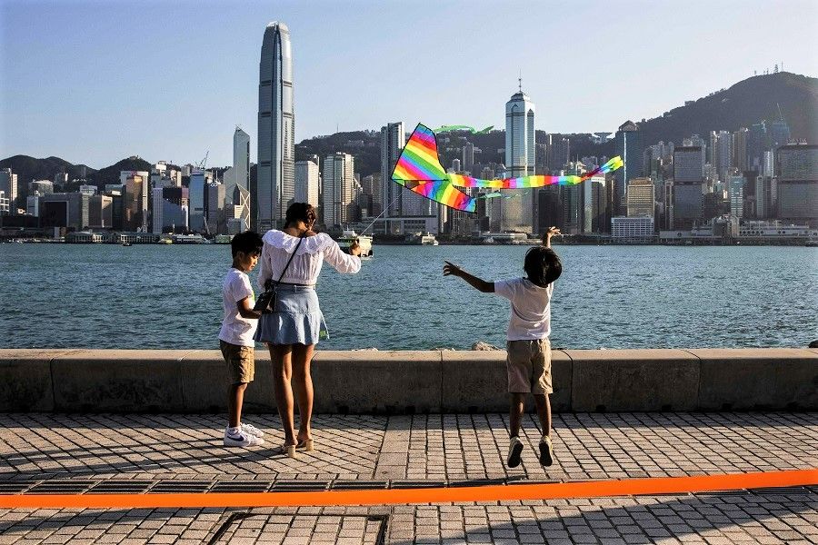 A child (right) jumps for a kite at the West Kowloon Cultural district overlooking Victoria Harbour in Hong Kong, China, on 27 October 2022. (Isaac Lawrence/AFP)