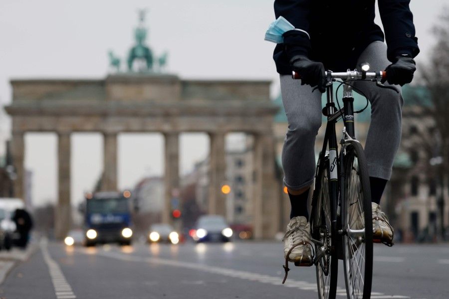 A cyclist is seen pedaling along the cycle path along the 17th June boulevard near the landmark Brandenburger Gate in central Berlin on 7 December 2020. (Odd Andersen/AFP)