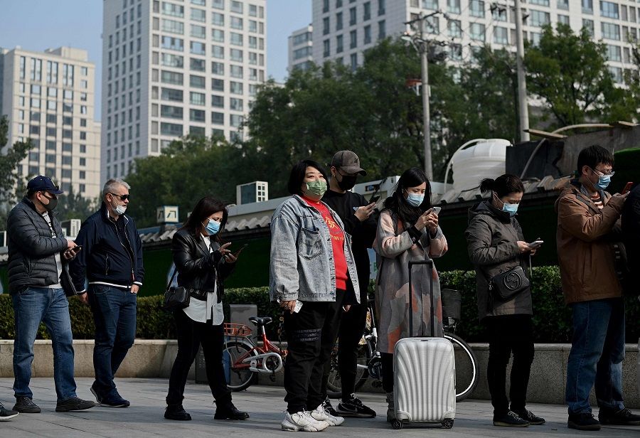 People wait in a queue to be tested for the Covid-19 coronavirus at a nucleic acid collection station in Beijing, China, on 25 October 2021. (Noel Celis/AFP)