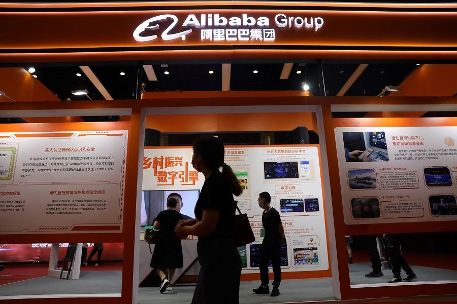 People walk past a booth of Alibaba Group at an exhibition during the China Internet Conference in Beijing, China, 13 July 2021. (Tingshu Wang/Reuters)