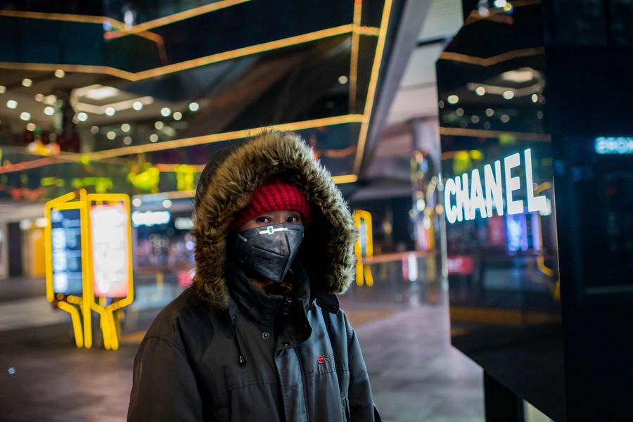 A woman wearing a protective mask walks in an empty shopping mall in the Sanlitun area in Beijing on 28 January 2020. (Nicolas Asfouri/AFP)